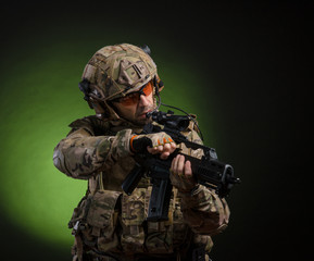 a male soldier in military clothes with a weapon on a dark background