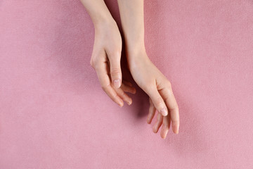 Woman with beautiful hands on pink fabric, top view