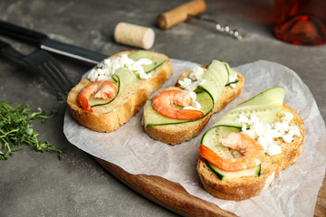 Cutting board of delicious bruschettas with shrimps on grey table