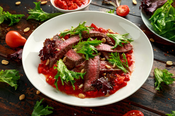 Beef Steak with Romesco sauce, nuts and vegetables on white plate