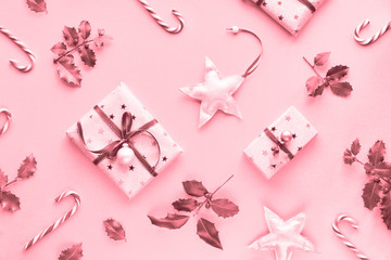 Fototapeta na wymiar Festive monochrome pink Christmas background with pink gift boxes, stripy candy canes, trinkets and decorative stars, geometric creative flat lay
