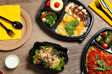 Lunchboxes with different meals on wooden table, flat lay. Healthy food delivery