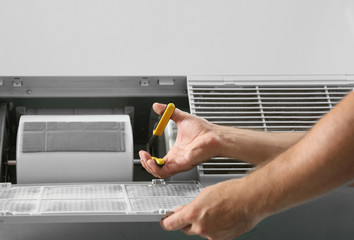 Professional male technician repairing air conditioner, closeup