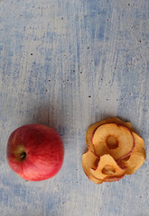 Homemade red Apple chips are a healthy treat for children, adults and vegetarians. Dry Apple slices and fresh fruit on a blue background.  Top view. Copy space.