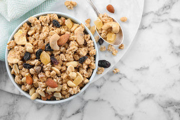 Bowl with healthy granola on white marble table, flat lay. Space for text