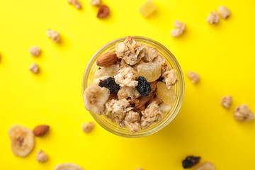 Jar with healthy granola on yellow background, flat lay