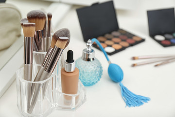 Different makeup products and bottle of perfume on white dressing table