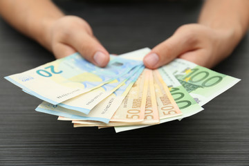 Man with Euro banknotes at table, closeup