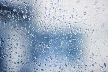 Raindrops on glass, background in blue tones