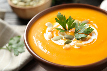 Delicious pumpkin soup in bowl on table, closeup