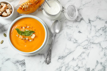 Delicious pumpkin soup in bowl on marble table, flat lay. Space for text