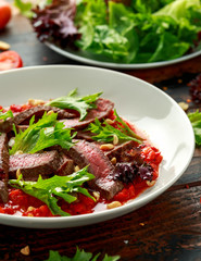 Beef Steak with Romesco sauce, nuts and vegetables on white plate