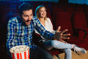 Attractive young caucasian couple watching a film at a movie theater, house or cinema. Look expressive, astonished and emotional. Sitting alone and having fun. Relation, love, family, weekend time.