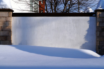 A lot of snow lies on a residential building and large snowdrifts around.