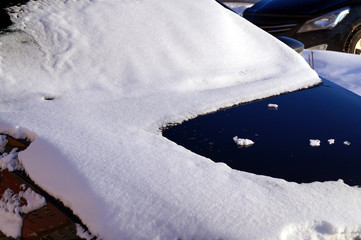 The car is covered in snow after heavy snowfall.