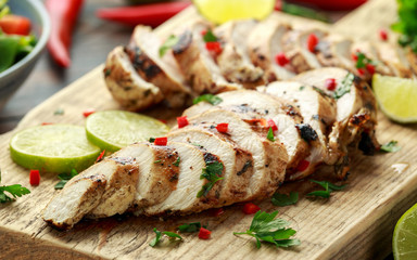 Homemade Grilled Chicken Breast in lime sauce with herbs on wooden board