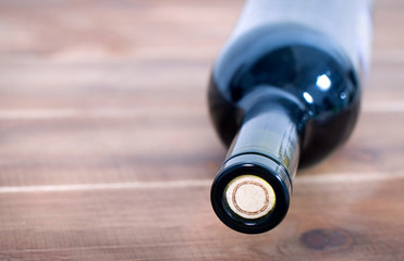 A closed bottle of wine with a cork lies on a wooden table close-up, macro