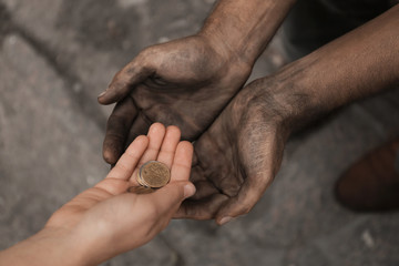 Woman giving poor homeless person money outdoors, closeup