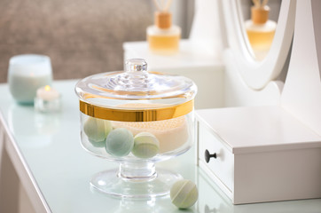 Jar with bath bombs and bath sponge on dressing table indoors