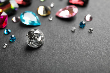 Different beautiful gemstones on black background. Space for text