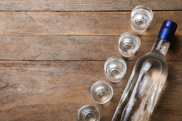 Bottle of vodka and shot glasses on wooden table, flat lay. Space for text © New Africa