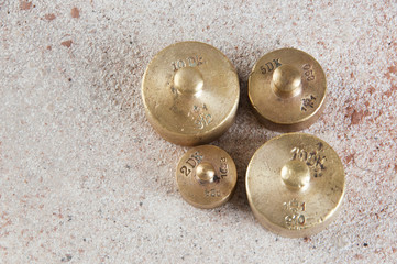 Antique bronze weights for scales on concrete background.