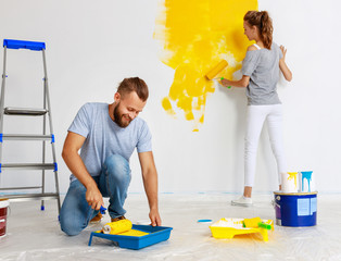 young happy couple is repairing and painting   wall at home.