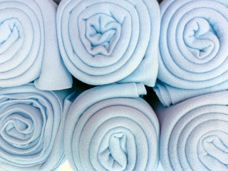 Fototapeta na wymiar Many rolled up blue colorful fleece blankets close up in a store, home comfort concept