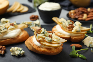 Delicious bruschettas with cheese, pear and nuts served on table, closeup