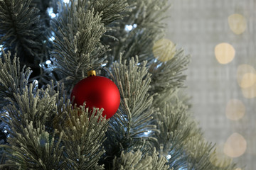 Beautiful Christmas tree decorated with festive lights and red ball, closeup