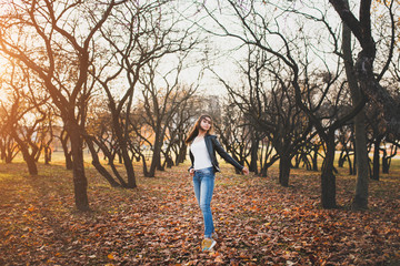 Cheerful slim attractive brunette is spinning in the park among the trees - happy woman in love