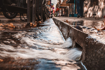 Stormy water on the sidewalk in a strong stream through curbs and in storm channels