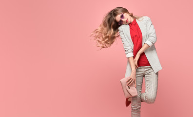 Fashionable blonde woman in Trendy autumn spring outfit, stylish hairstyle, makeup. Joyful lady in jacket dance on pink. Cheerful girl, stylish fashion accessories, beauty style