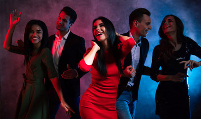 Young and gracious. A pleasant company of five well-dressed multicultural friends is dancing in the...