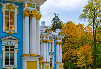 A fragment of a blue Baroque pavilion with white columns on the background of autumn trees on the...
