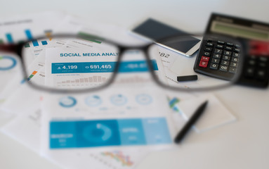 Blurred social media analytics on office desk, gets clear  through the glasses