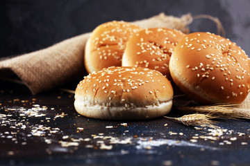 Fresh homemade burger buns with sesame on dark background