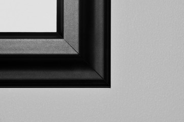 Black picture frame corner in the upper right with gray negative space surrounding it. Black and white image.