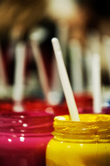 Jars with multi-colored paints background vertical