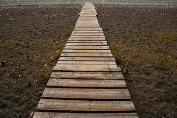 Wooden path on the sandy beach. Beach boardwalk with sand texture background