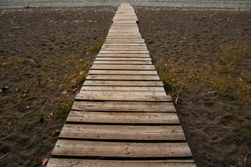 Obraz premium Wooden path on the sandy beach. Beach boardwalk with sand texture background