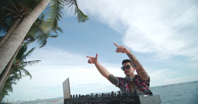 Happy asian male DJ playing music on a beach party.