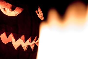 Fototapeta premium Carved spooky halloween pumpkin in hot burning hell fire flames. Big helloween autumn symbol with mad face, glowing eyes, mouth and teeth. Scary hot nightmare horror with evil smile at october 31st