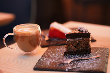 Showcase with cakes and sweets. Cupcakes and cupcakes on a showcase in the refrigerator. A slice of cake with a cup of coffee in a cafe. Cake snickers and strawberry cake. Dessert in a restaurant