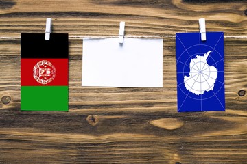 Hanging flags of Afghanistan and Antarctica attached to rope with clothes pins with copy space on...