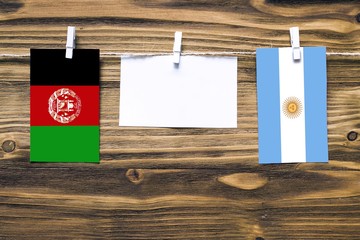 Hanging flags of Afghanistan and Argentina attached to rope with clothes pins with copy space on...