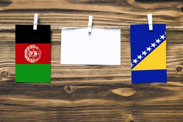 Hanging flags of Afghanistan and Bosnia Herzegovina attached to rope with clothes pins with copy...