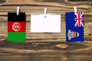 Hanging flags of Afghanistan and Cayman Islands attached to rope with clothes pins with copy space...