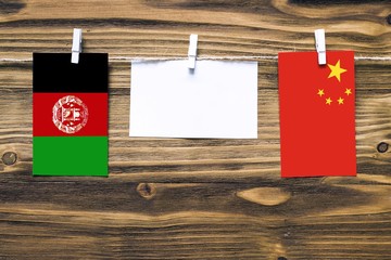 Hanging flags of Afghanistan and China attached to rope with clothes pins with copy space on white...