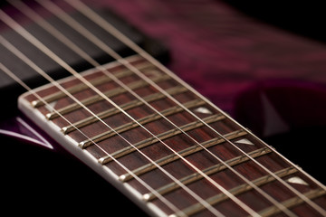 Fototapeta premium Fretboard of modern electric guitar on black background. 